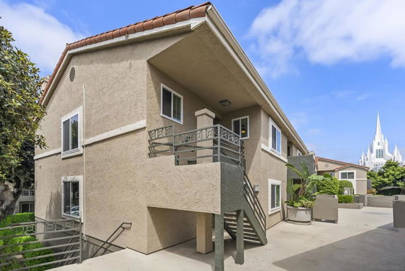 Front view of a two-story building with a staircase and balcony.