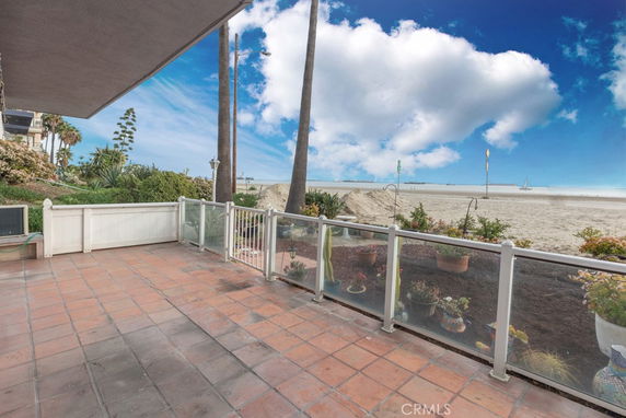 Panoramic view of a beachfront patio with glass railing overlooking the beach and ocean.