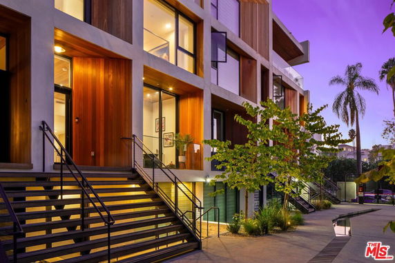 Front view of a modern multi-story building with large windows and wooden accents.