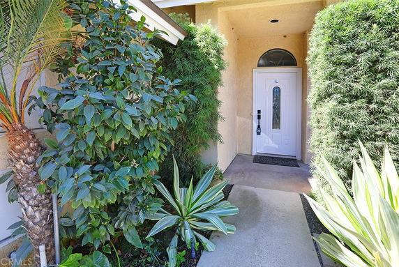 Front view of a house with a white door and surrounding greenery.