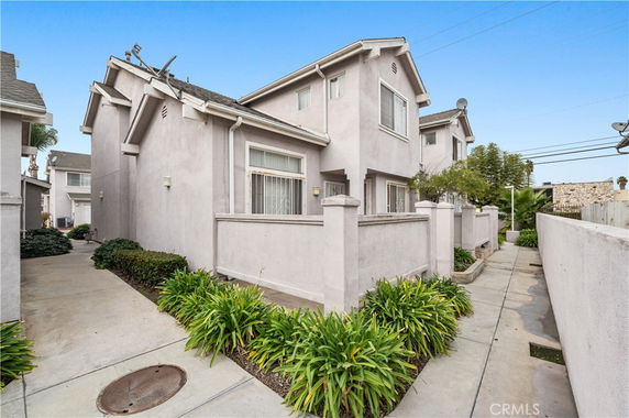 Front view of a two-story house with a stucco exterior and sloped roof.