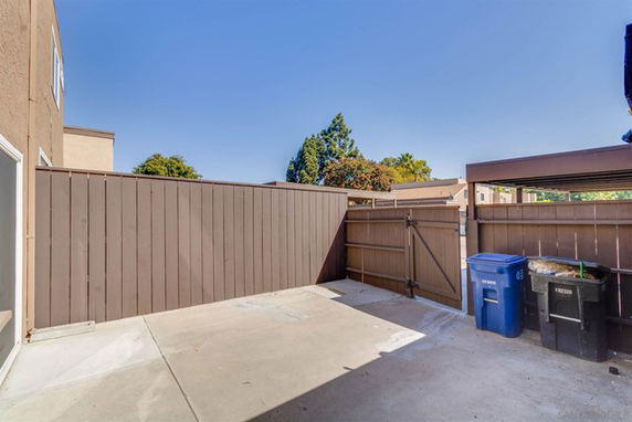 Outdoor parking area with wooden fencing and waste containers.