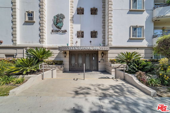 Front view of a building with ornate entryway and surrounding plants.