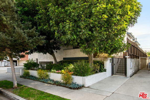 Front view of a building with a gated entrance and surrounding trees.
