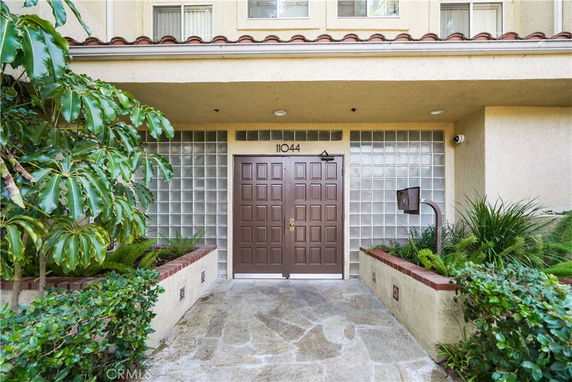 Front view of a multistory building entrance with a brown door and glass block windows.