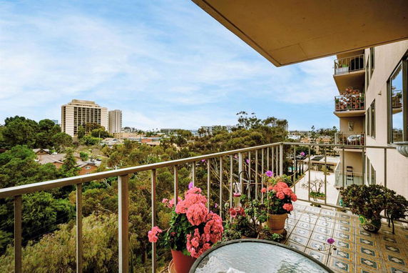 View from a balcony showing buildings and a natural landscape in the background.