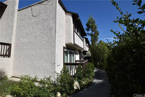 Side view of a two-story residential building with textured walls and wooden balconies.