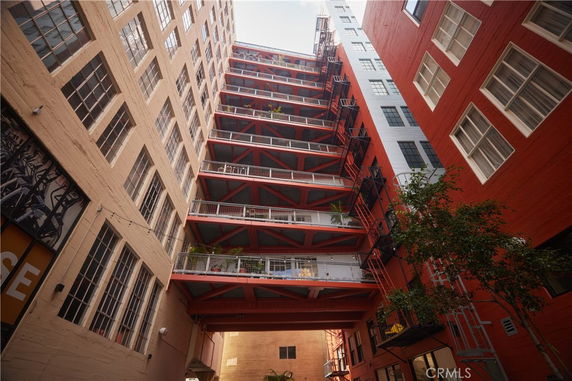 Upward view of a multi-story building with red accents and fire escapes.