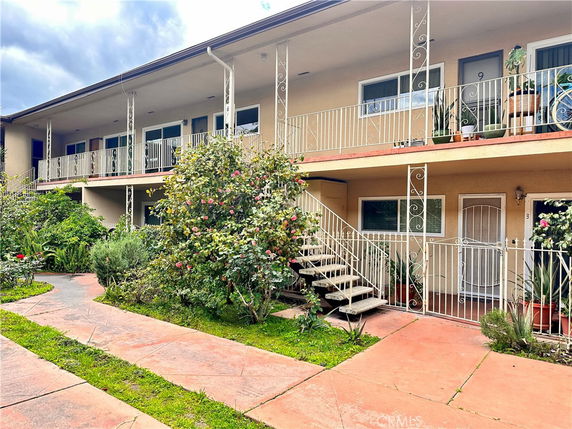 Front view of a two-story building with balconies and stairway entrance.