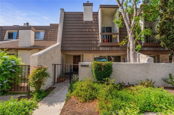 Front view of a townhouse with a brown sloped roof and gated entry.