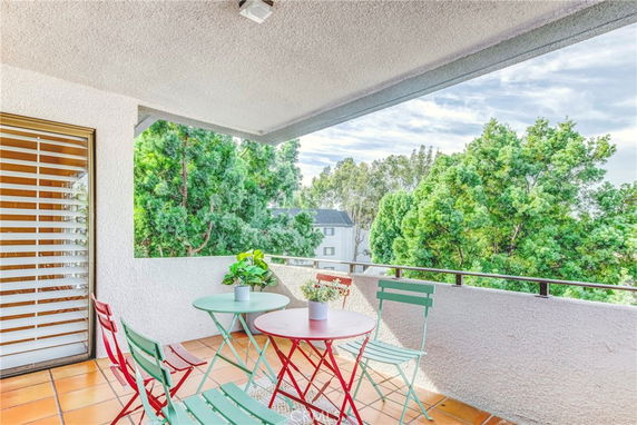 Balcony area with outdoor seating and view of lush trees.