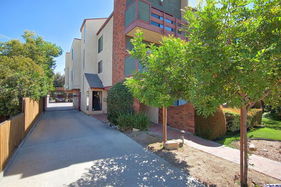 Front view of a multi-story building with brick and stucco exterior, featuring a gated driveway entrance.