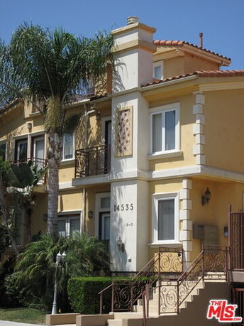 Front view of a multi-story house with ornate railings and decorative elements.