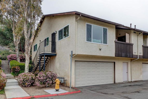 Front view of a two-story building with a garage and external staircase.