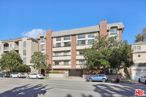 Front view of a multi-story apartment building with a brick facade and arched windows.