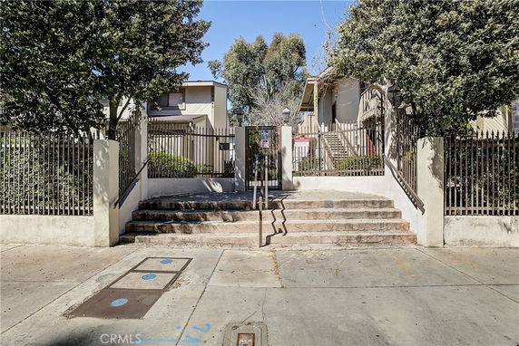 Front view of a multi-story building with steps leading to a gated entrance.
