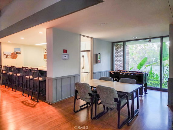 Interior view of a recreation area with a foosball table, dining table, and bar seating.