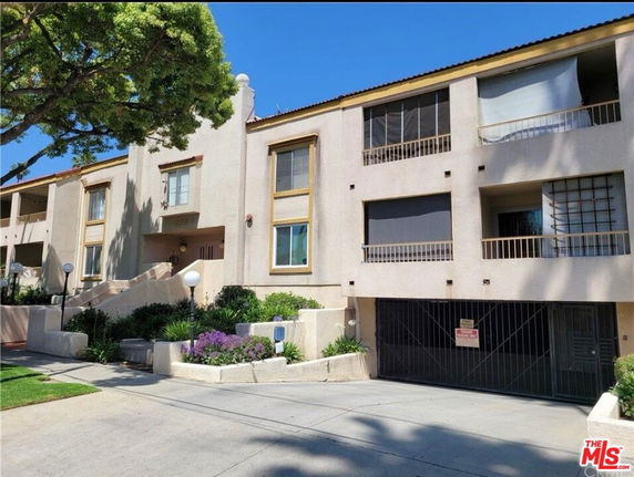 Front view of a multi-story residential building with balconies and a gated entrance.
