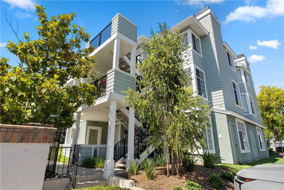 Front view of a multi-story residential building with a light green facade and outdoor staircases.