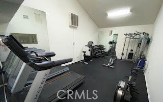 Room with gym equipment including treadmills and weight machines.