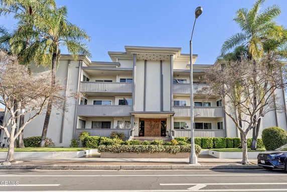 Front view of a multi-story residential building with a central entrance and balconies.