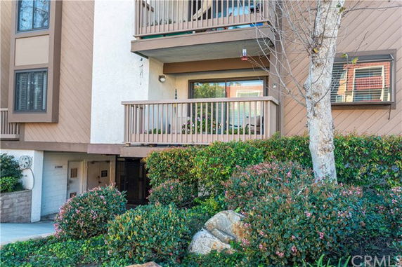 Front view of a multi-story residential building with balconies and landscaped surroundings.