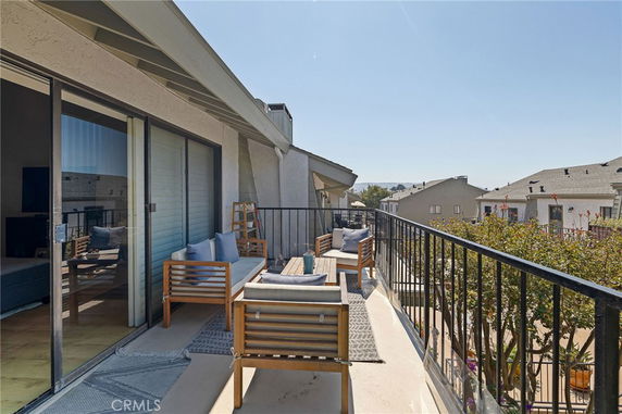 Balcony with outdoor seating overlooking surrounding residential buildings.