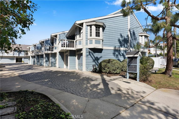 Front view of a multi-story blue house with balconies and a driveway.