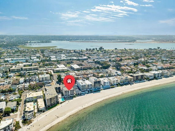 Panoramic aerial view of a beachfront area with several multi-story buildings.