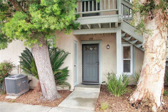 Front view entrance of a two-story building with stairs and plants.