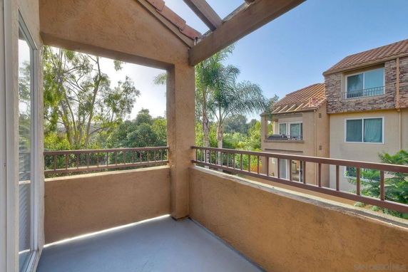 View from a balcony overlooking surrounding trees and buildings.