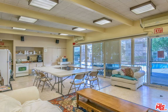 Interior view of a clubhouse with tables, chairs, and a small kitchen area.