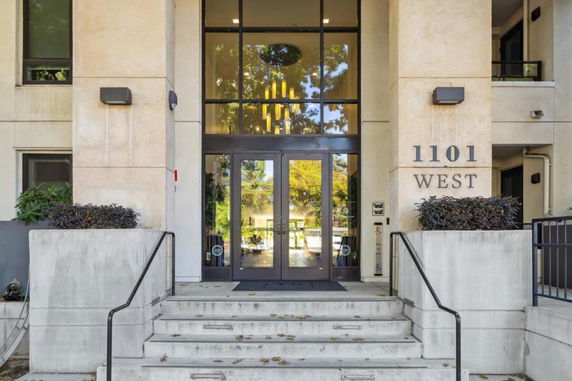 Entrance view of a modern building with glass doors and concrete steps.
