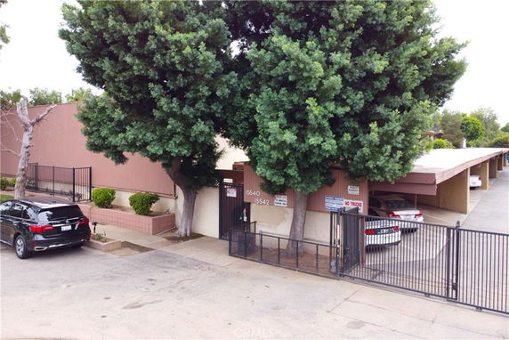 Front view of a building with gated entrance and covered parking area.