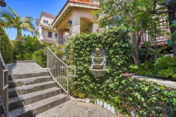 Front view of a multi-story house with a tiled entrance staircase and decorative wall sculpture.