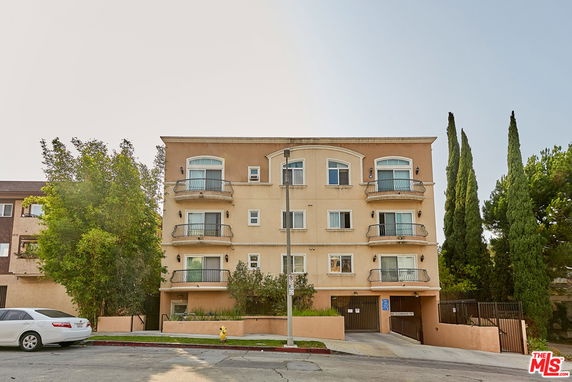 Front view of a multi-story building with balconies and a gated entrance.