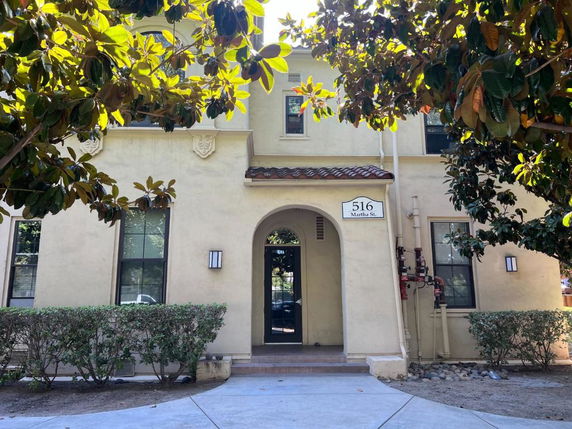 Front view of a two-story building with an arched entrance and a tile roof.