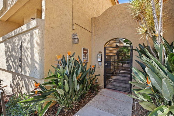 Front view of a building with an arched entrance gate and surrounding plants.
