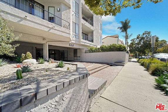 Front view of a multi-story residential building with balconies and landscaping.