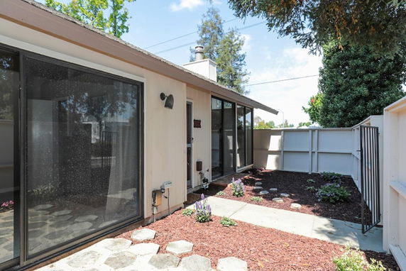Front view of a single-story house with large sliding glass doors and a small garden area.
