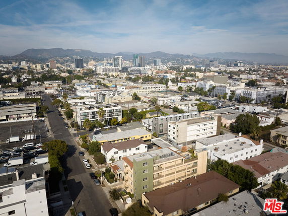Aerial view of an urban area with various buildings and a hilly backdrop.