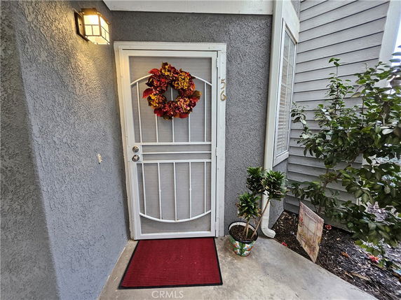 Front view of a house entrance with a screen door and a seasonal wreath.