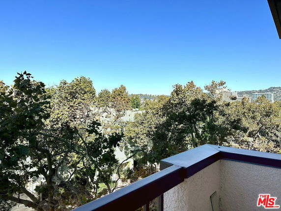 Panoramic view from a building showing trees and distant cityscape.