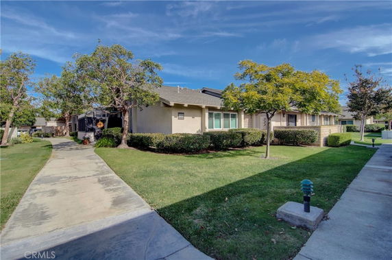 Front view of a single-story house with a pathway and shrubs in the front yard.