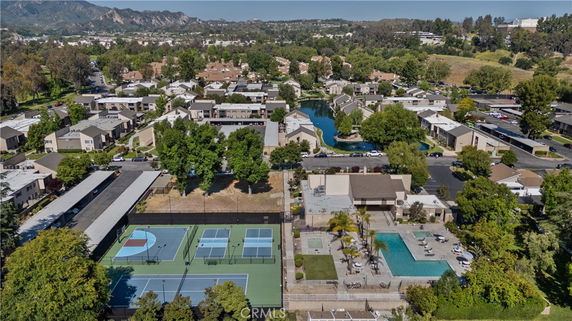 Aerial view of a residential area with a clubhouse, swimming pool, tennis courts, and surrounding houses.