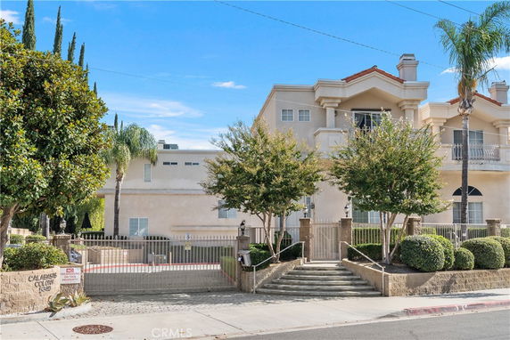 Front view of a multi-story house with gated entrance and balconies.
