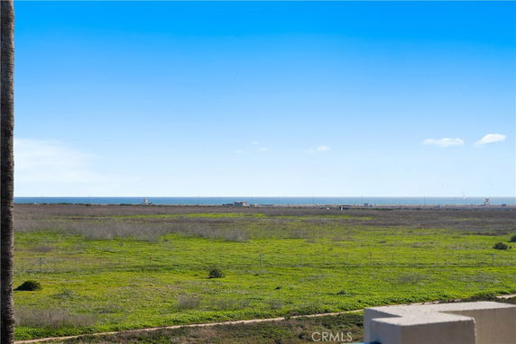 Panoramic view of grassy field leading to the ocean under a clear blue sky.