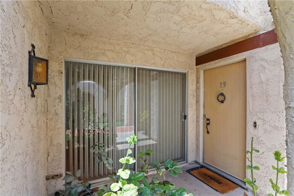 Front entrance area of a house with a sliding glass door and a wooden main door.