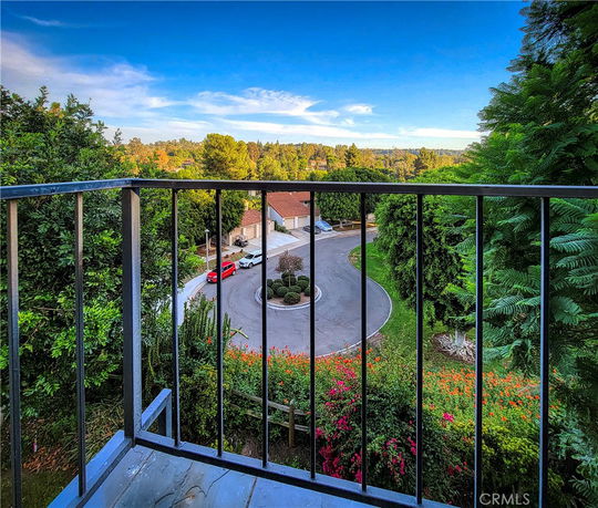 View from a balcony overlooking a suburban street and lush green surroundings.