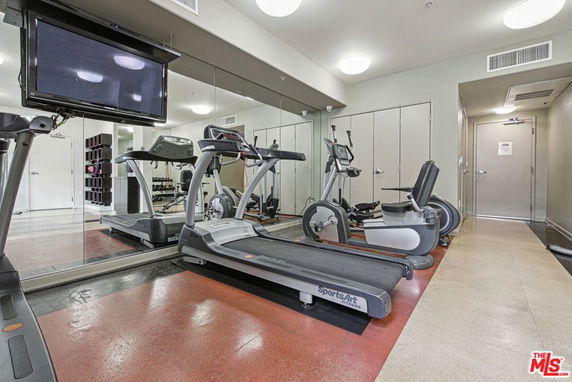 Indoor gym area with exercise equipment and a wall-mounted TV.